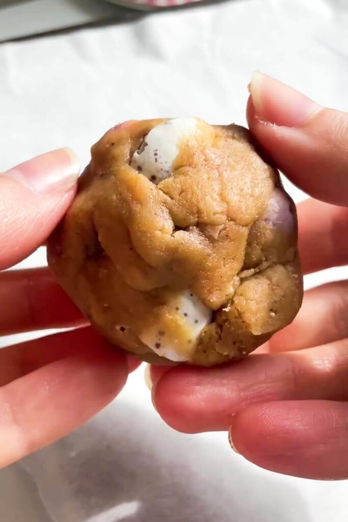 Hands rolling cookie dough ball.